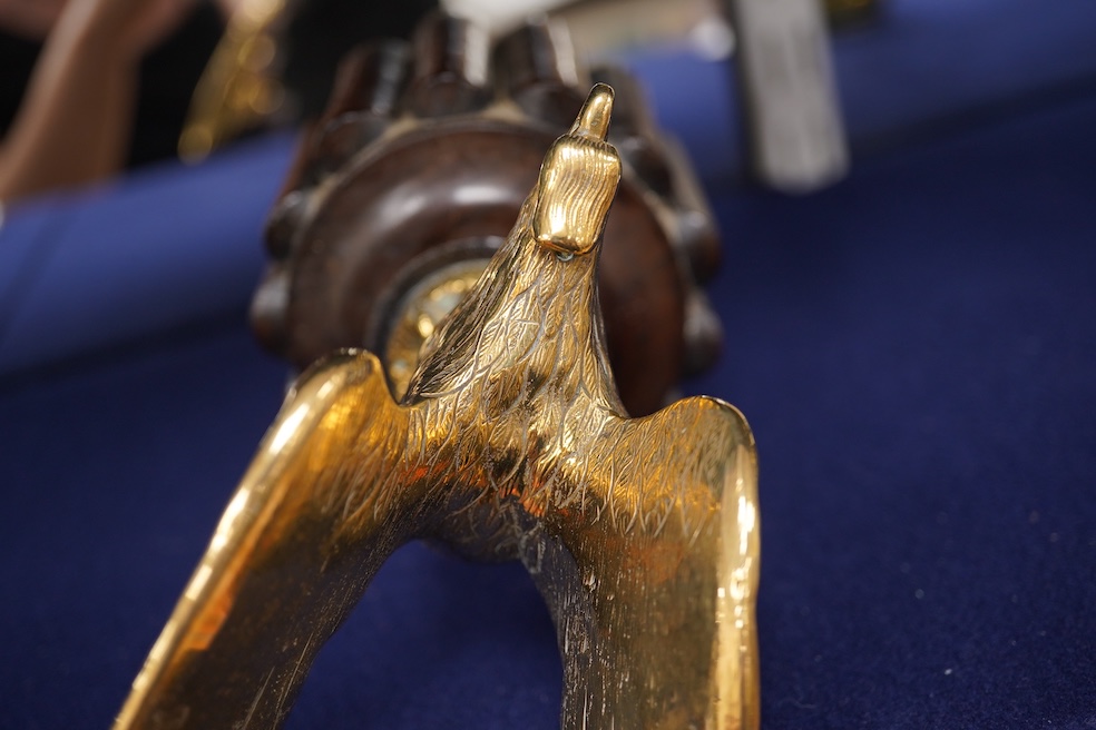 Two brass car mascots in the form of eagles, one mounted on a threaded radiator cap, the other mounted on a wooden base, the larger with a wingspan of 31cm. Condition - fair, one eagle with bent wing.